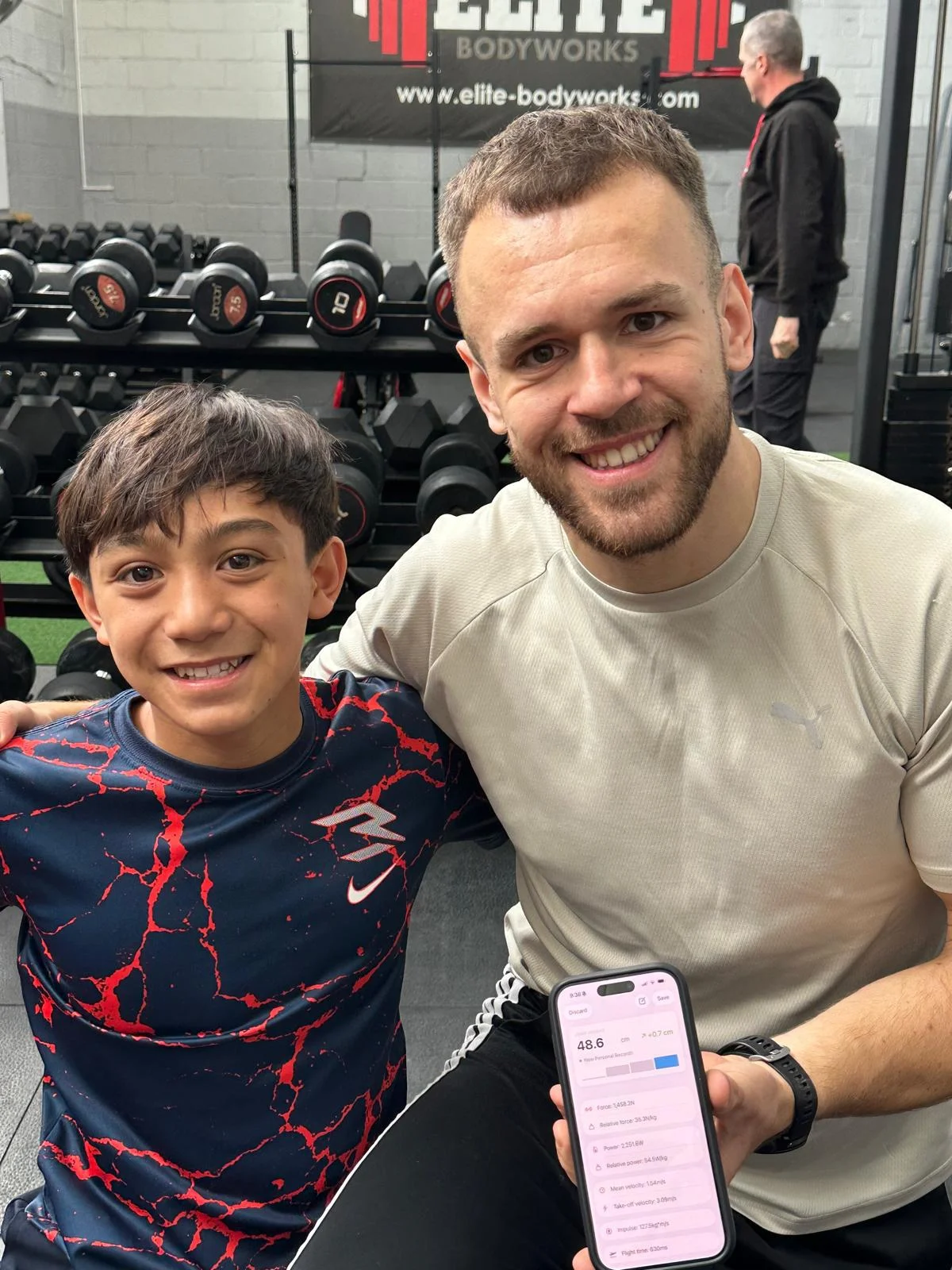 Coach Jordan Dunne showing performance metrics to a youth athlete on a mobile app
