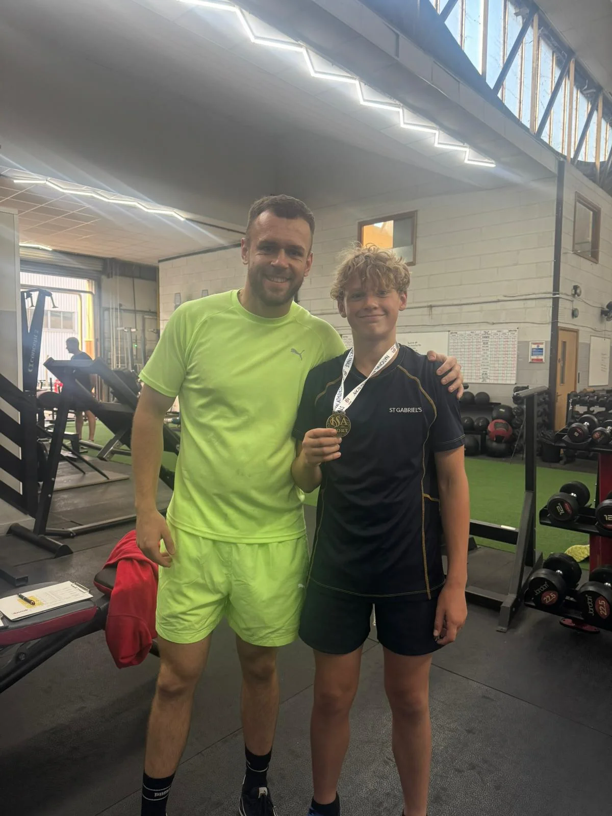 Young athlete celebrating a sports medal achievement with coach Jordan Dunne